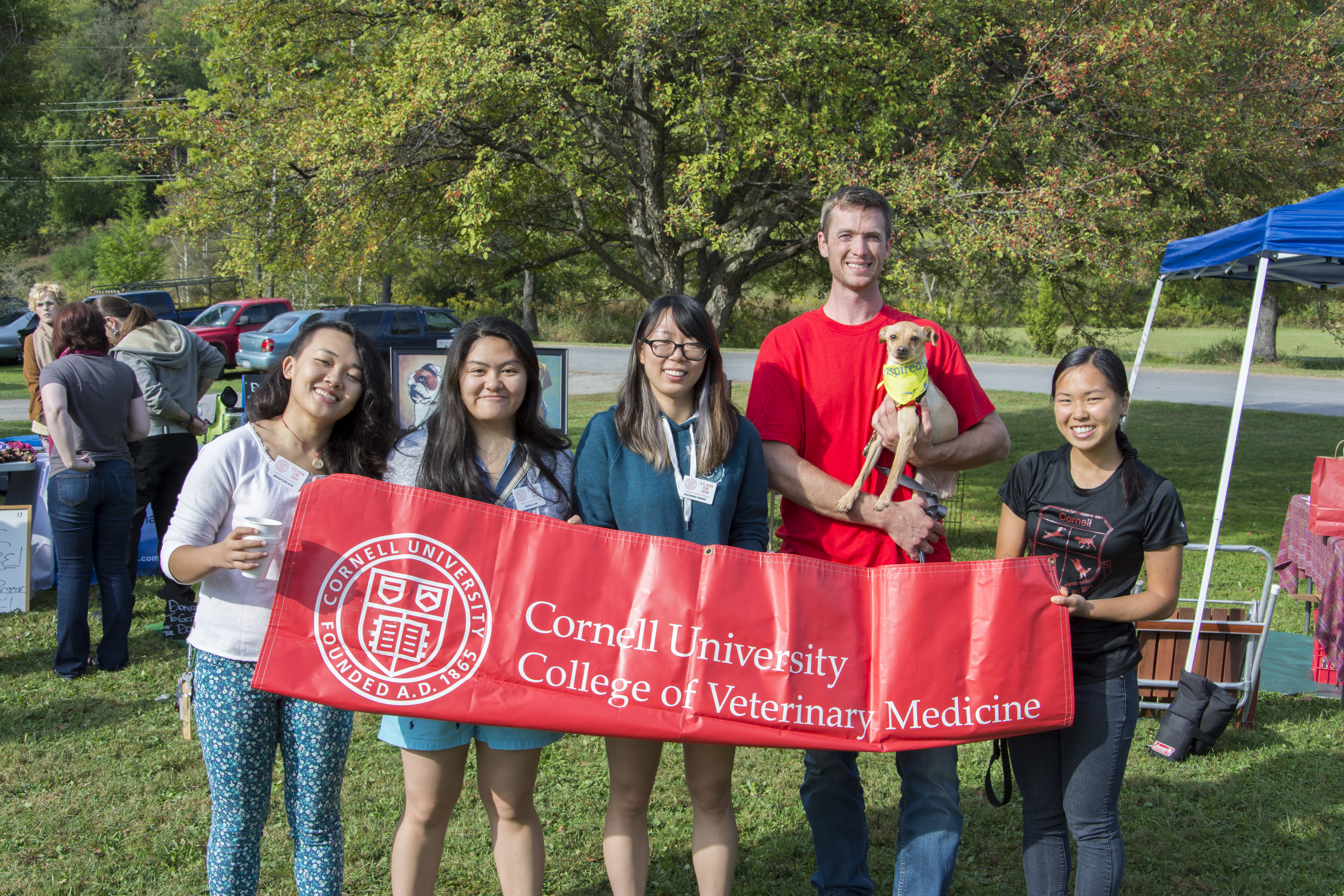 five veterinary students holding a CVM banner at a community event