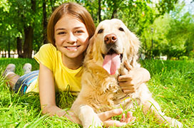 Young girl laying on grass with golden retriever