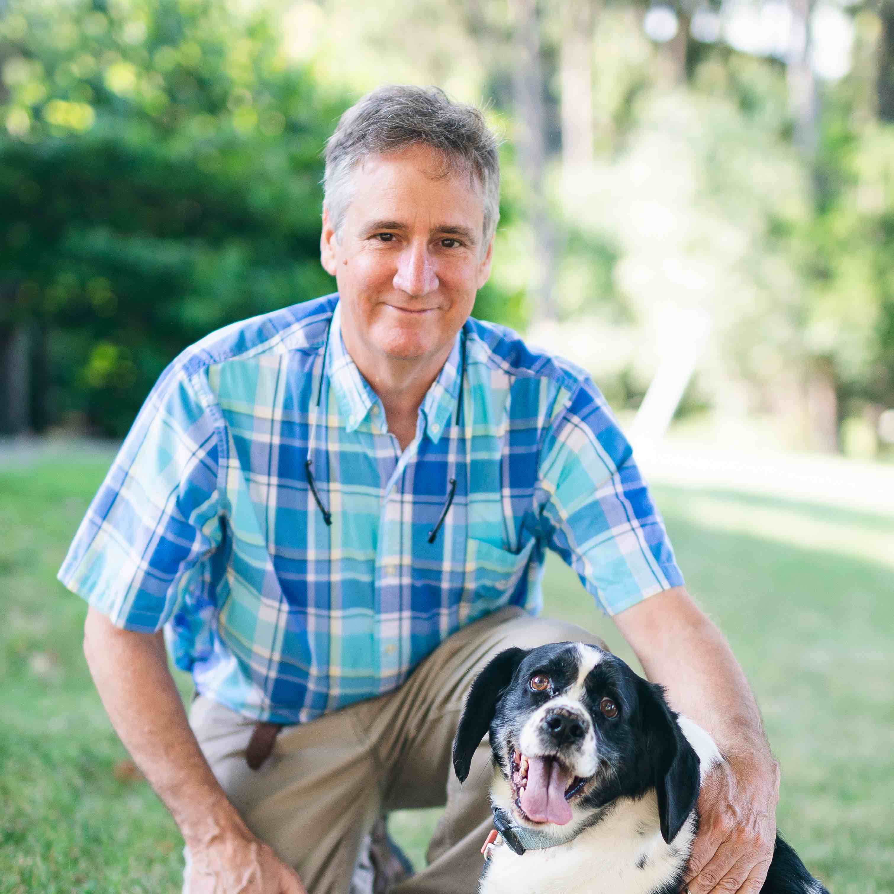 Dr. Coonrod on one knee with his one hand over his canine