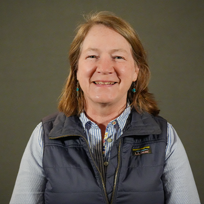 Headshot showing a woman against a gray background. 