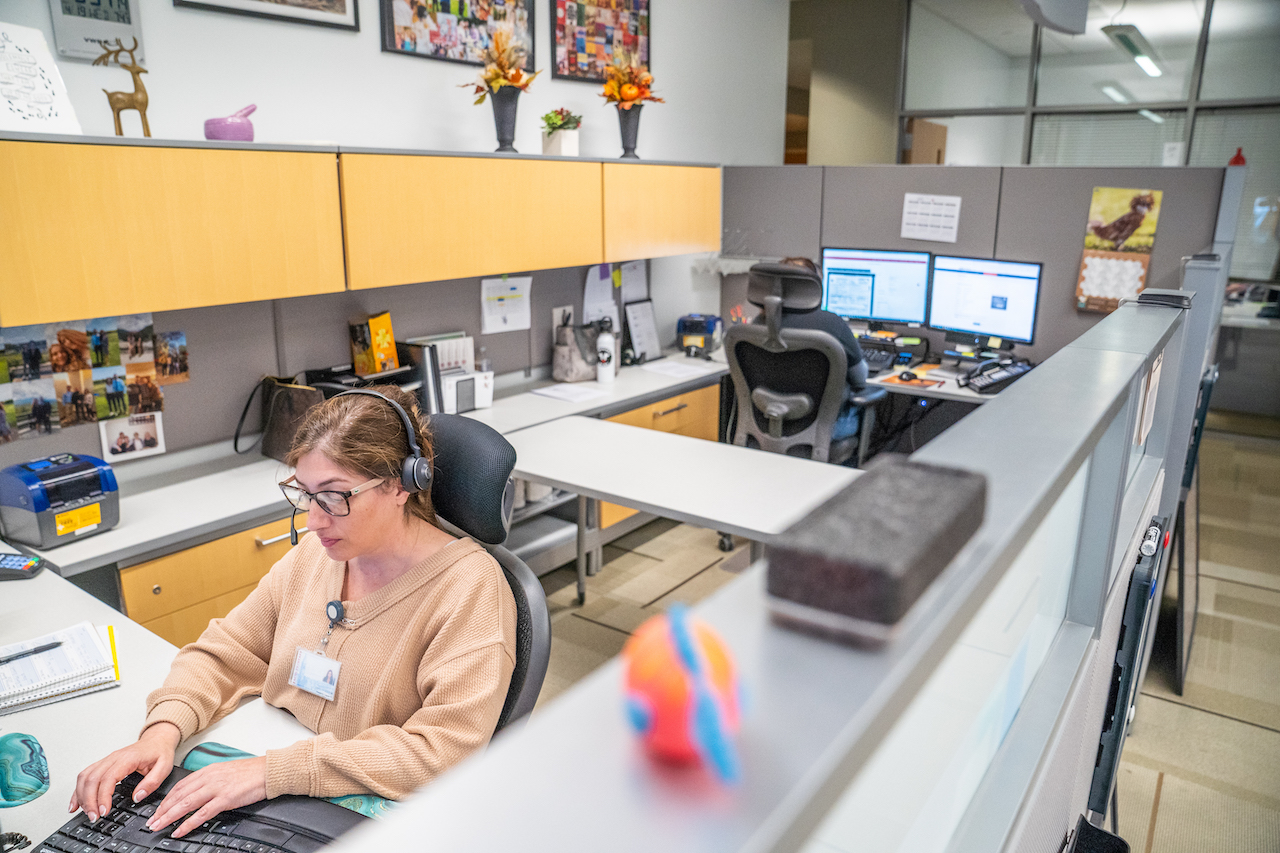 Two staff members in a cubicle at the AHDC answering phone calls from clients