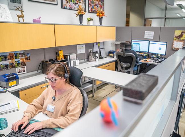 Two staff members in a cubicle at the AHDC answering phone calls from clients