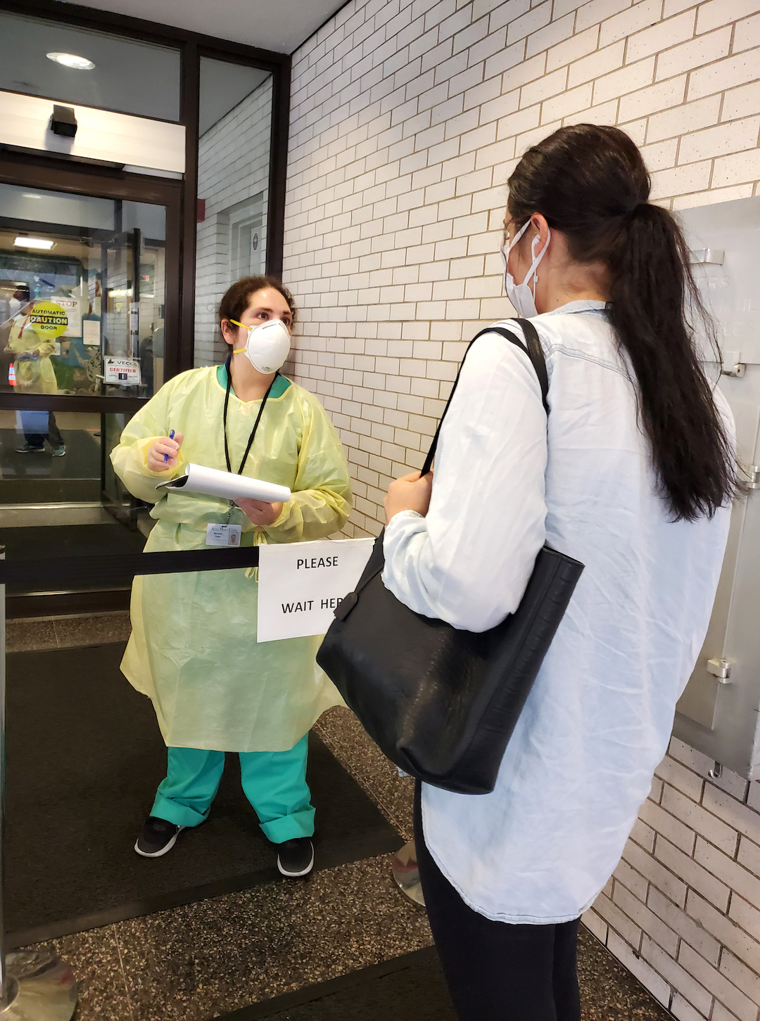 A masked staff member greets a client at the entrance to AMC