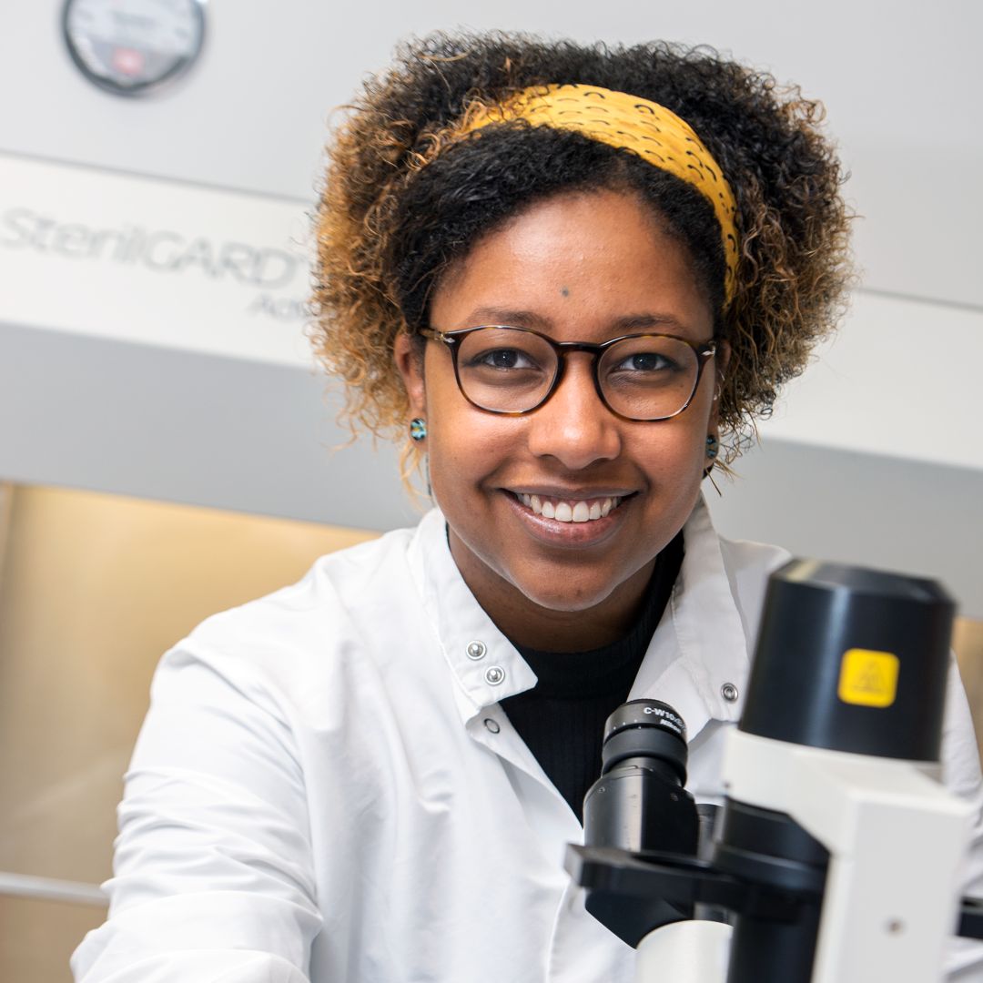 Scientist looking at viewer while using microscope