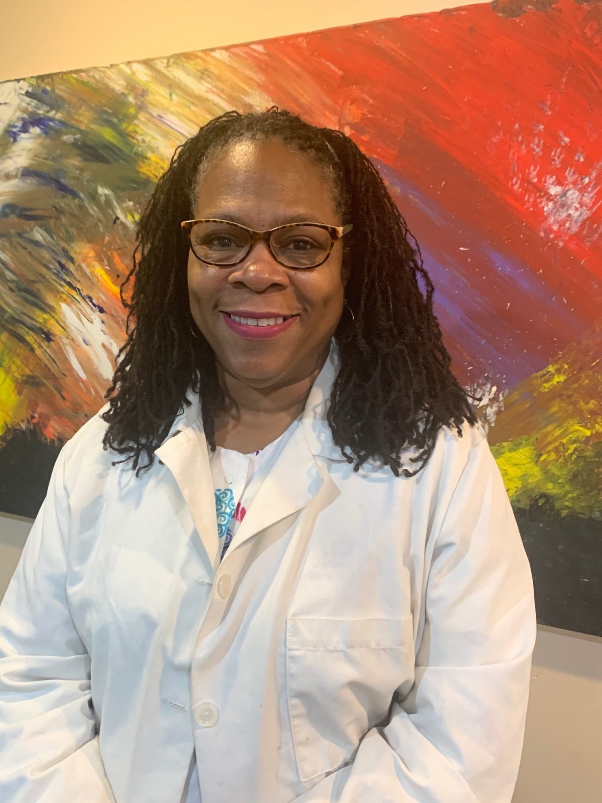 Dr. Butler in a white coat with a colorful painting in the background