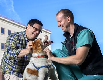 A vet and client smiling with a dog