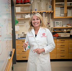 Lisa Fortier at a whiteboard in a lab coat