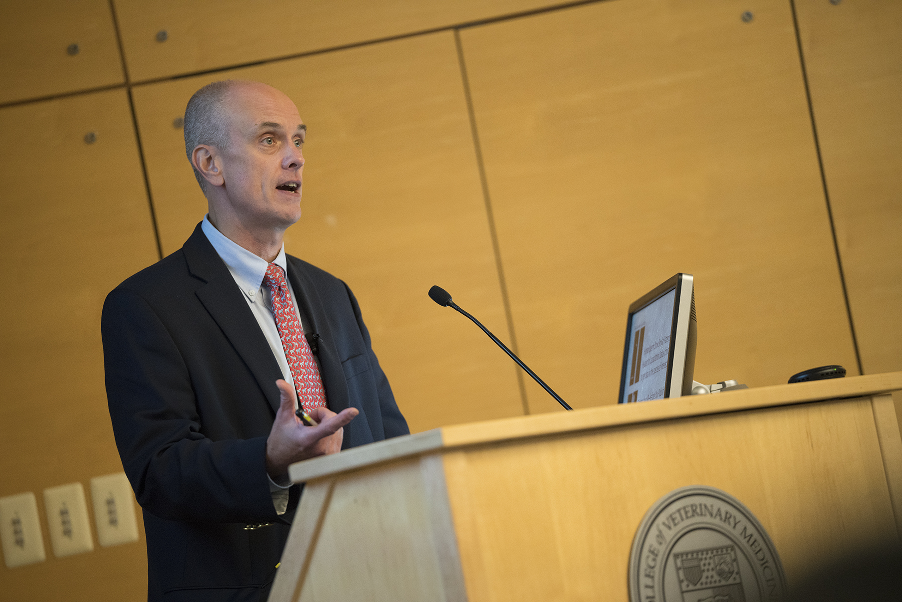 Dr. Alexander Travis speaking at a podium