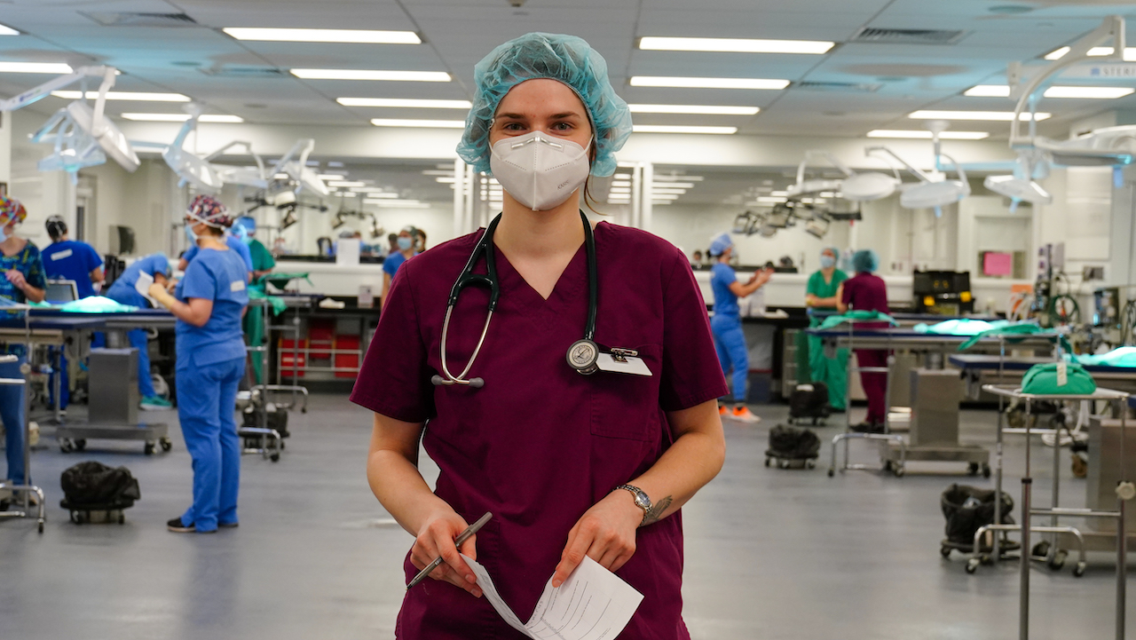 Makayla Watros, a veterinary student, in the surgery room in purple scrubs