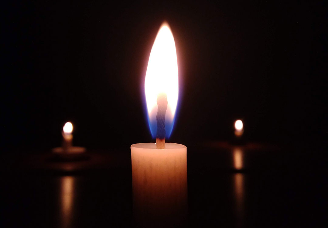 Three candles lighting a dark room