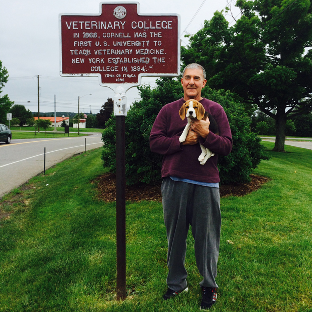 picture of Dr. Mark Helfat standing in front of Cornell Vet College established sign 