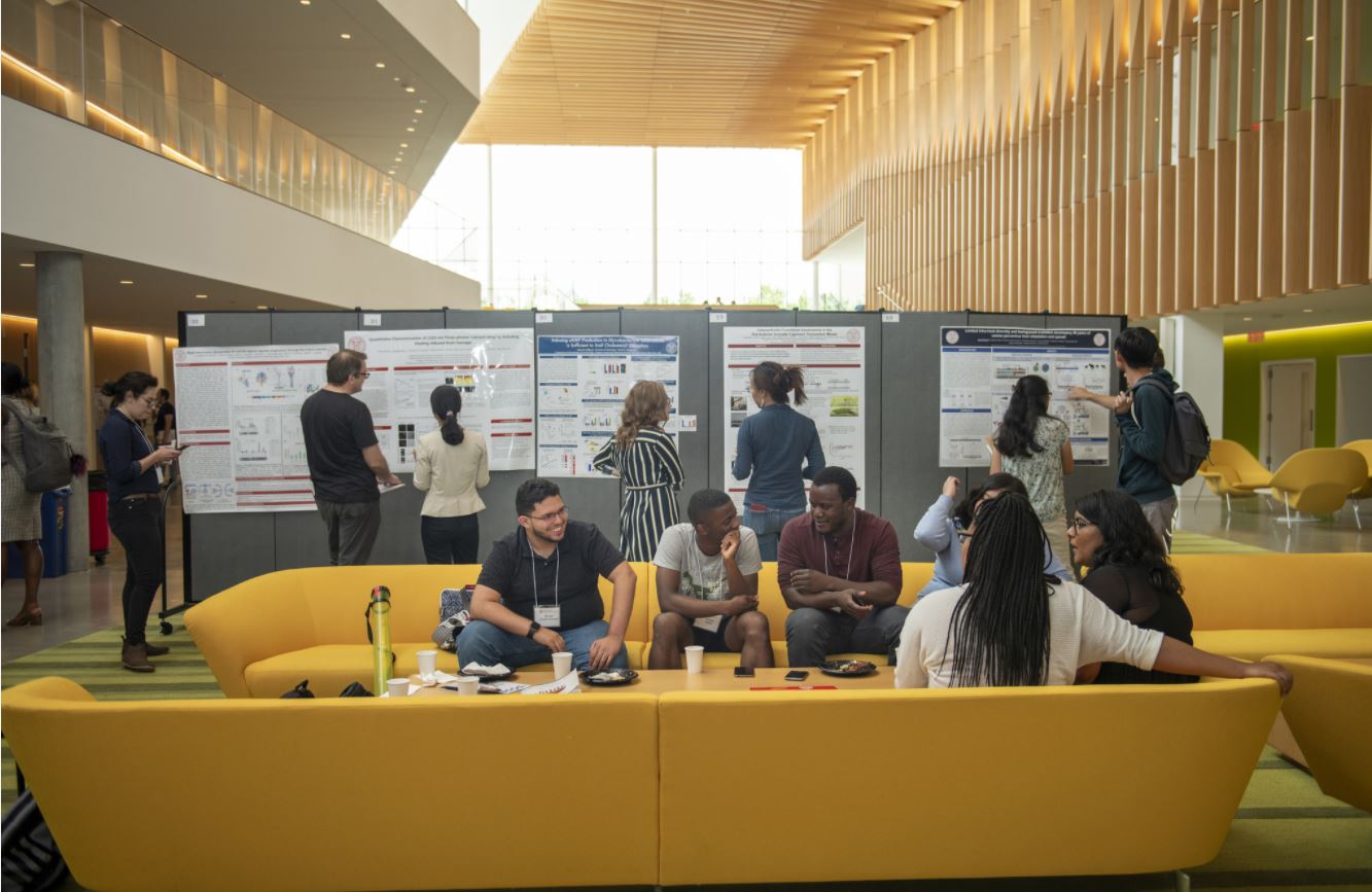 graduate students talking on a yellow couch at a poster session