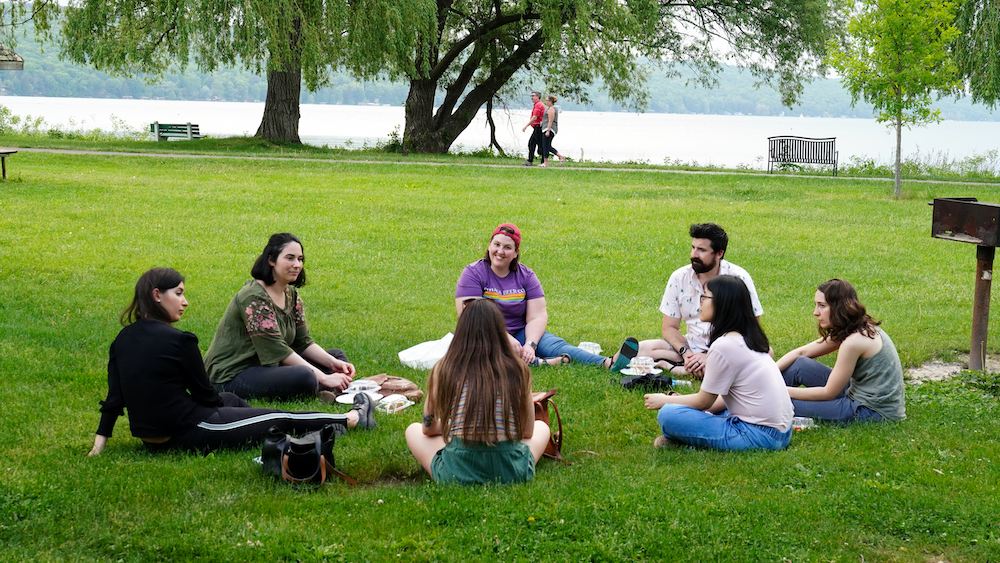 Six members of the MPH program seated in the grass in a circle at Stewart Park