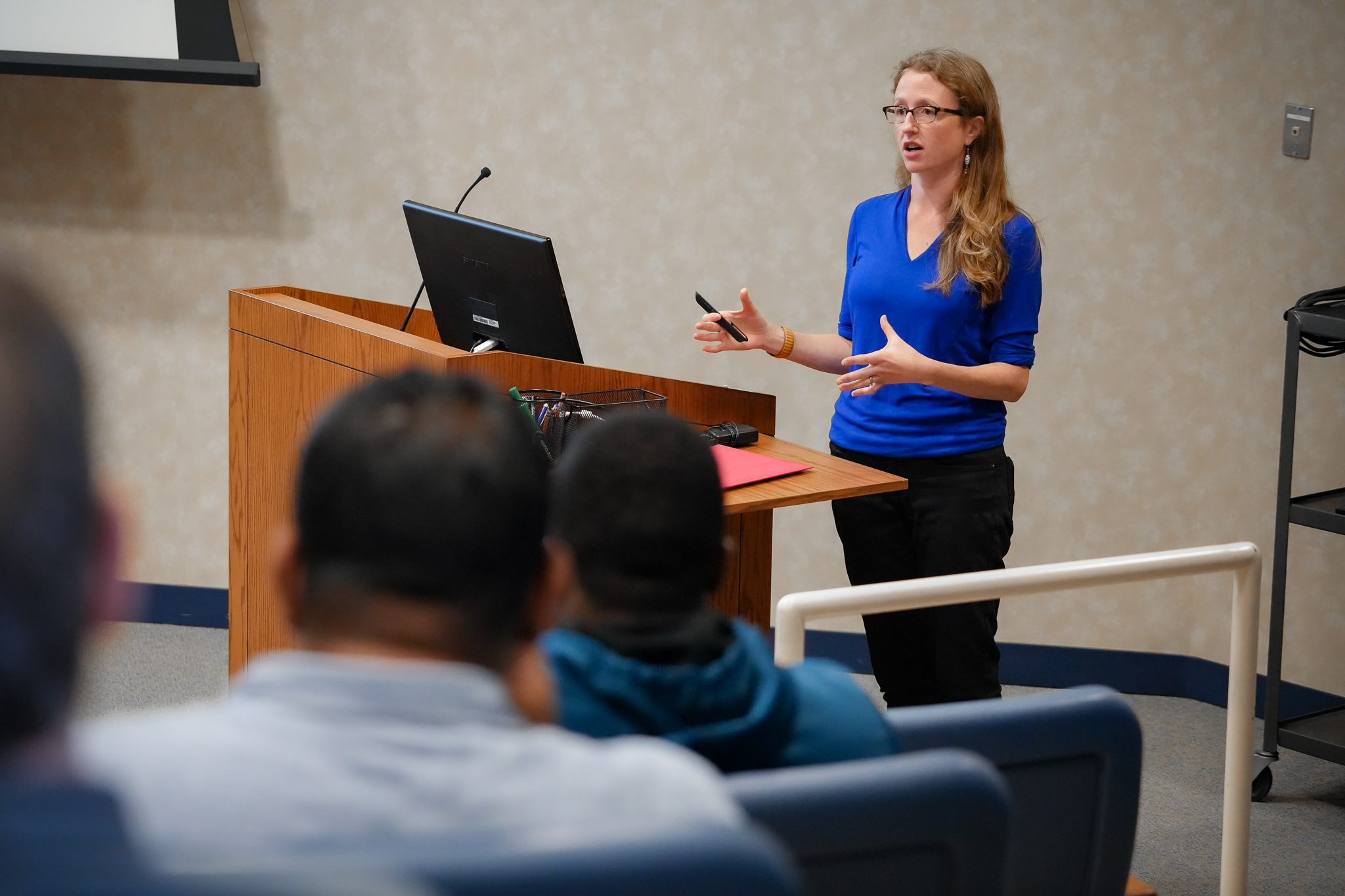  Dr. Sarah Caddy stands at the podium in the Thaw Lecture Hall. 