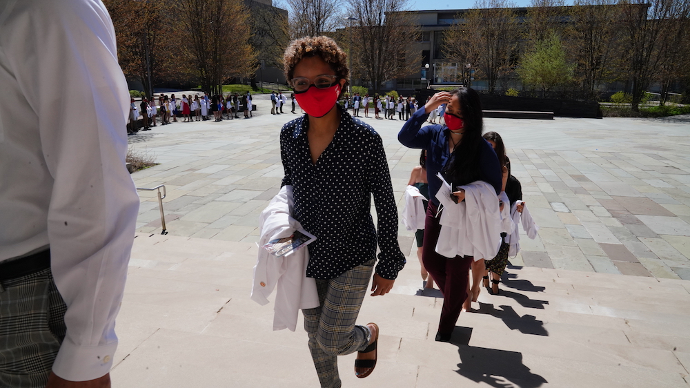 Students walking into Bailey hall carrying their white coats