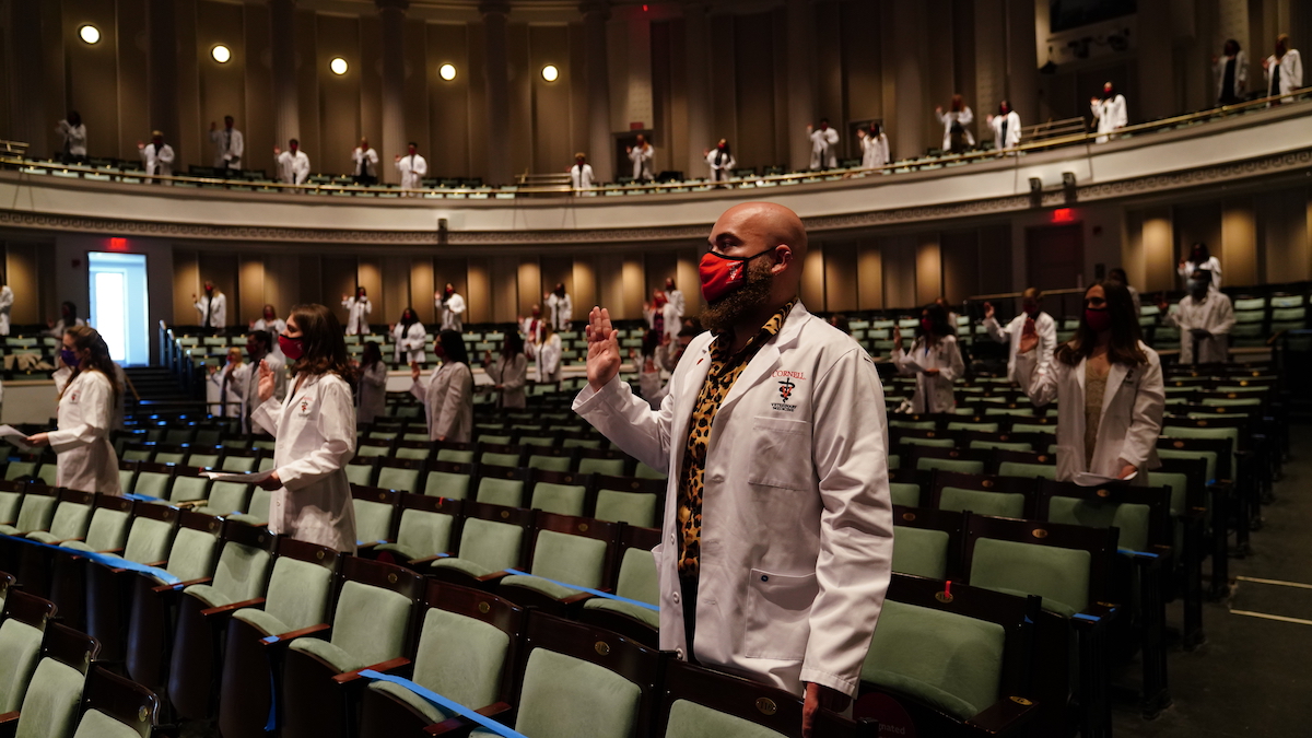 Veterinary students in white coats in Bailey Hall recite the Veterinarian's oath