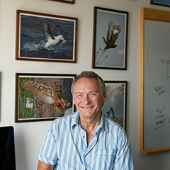 David Russell at his desk with pictures in the background