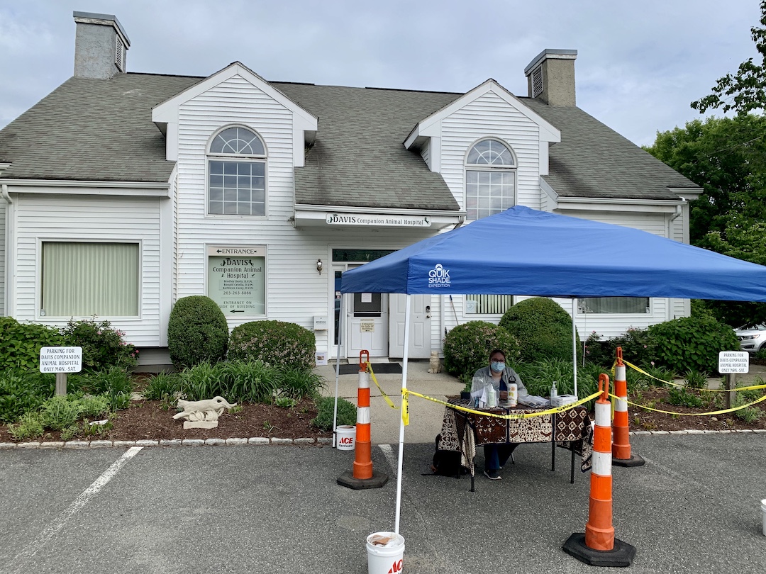 The front exterior of the Davis Veterinary Hospital, which has a canopy set up with a work seated beneath it to accommodate the new pandemic check-in process