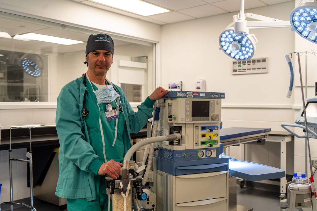 Dr. Luis Campoy stands next to an anesthesia machine