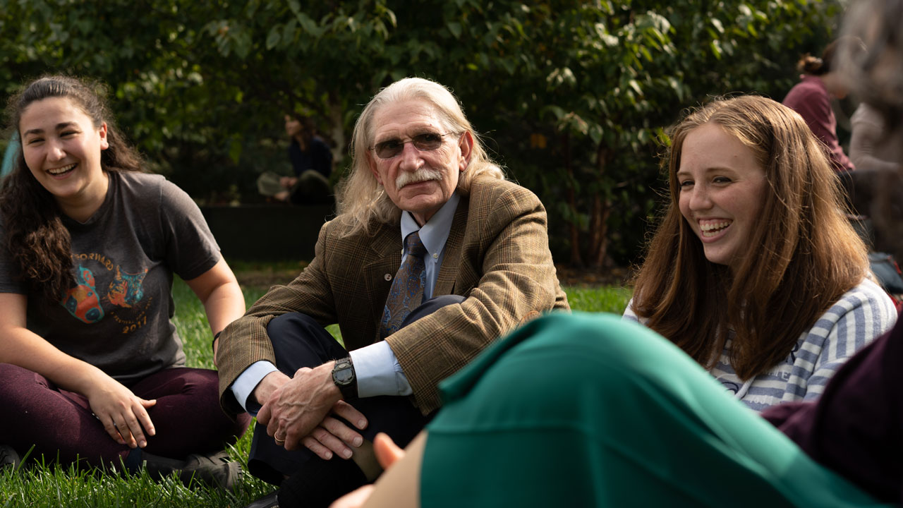 Dr. Dwight Bowman seated in an exterior courtyard with students