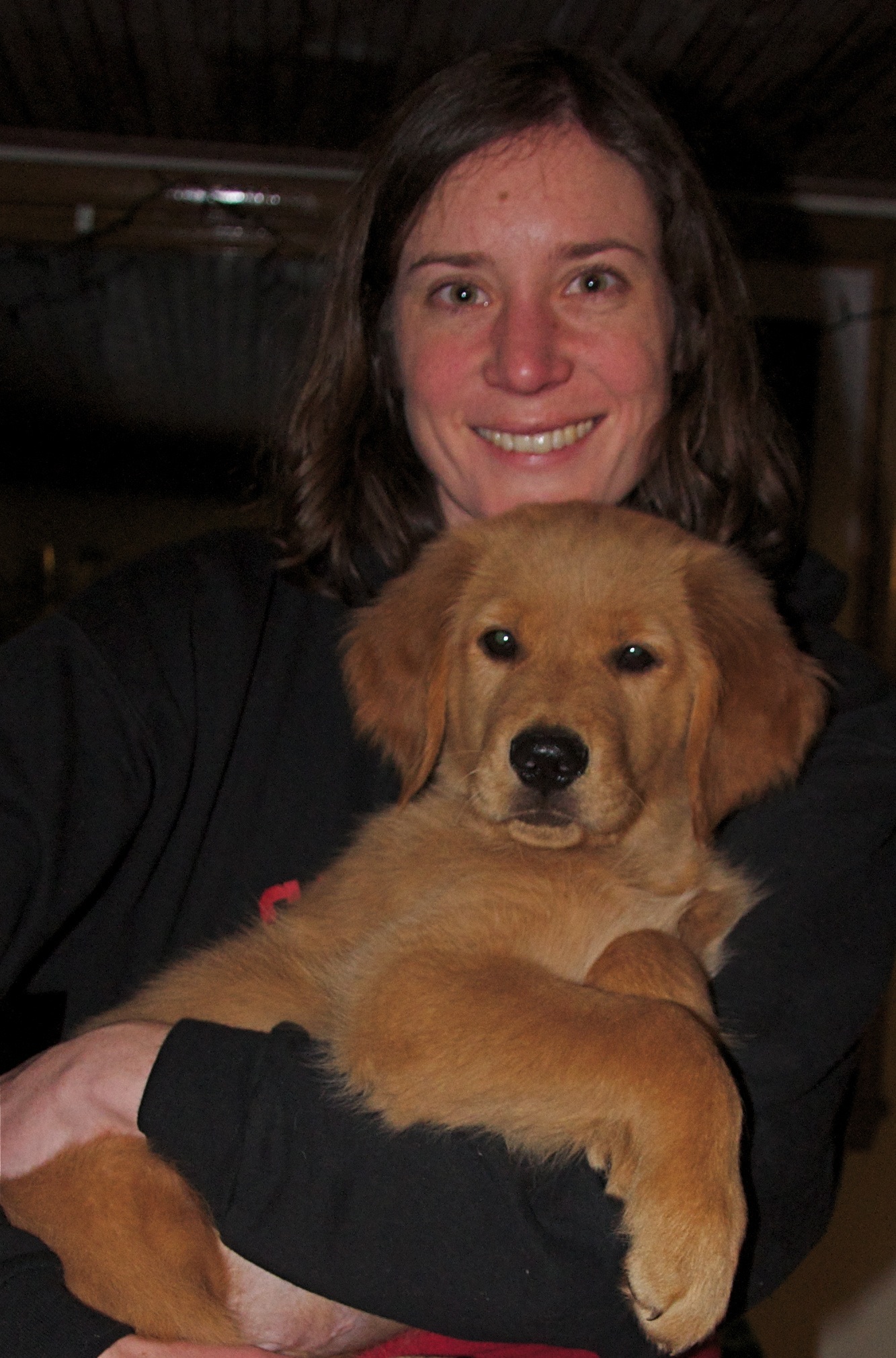 Jessica Hayward holds a golden retriever puppy in her lap