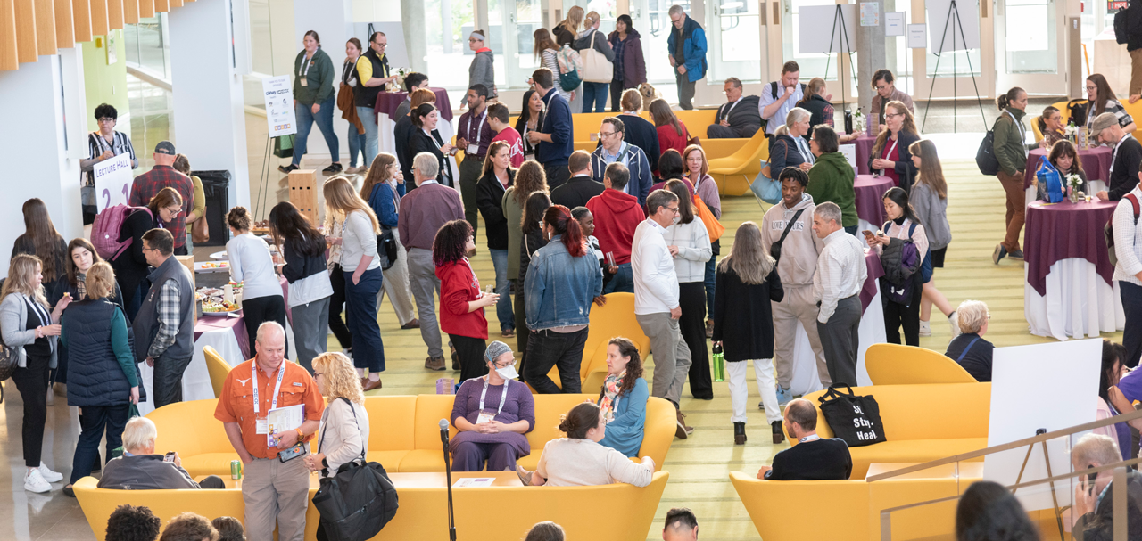 A crowd of conference attendees mingling in the CVM atrium