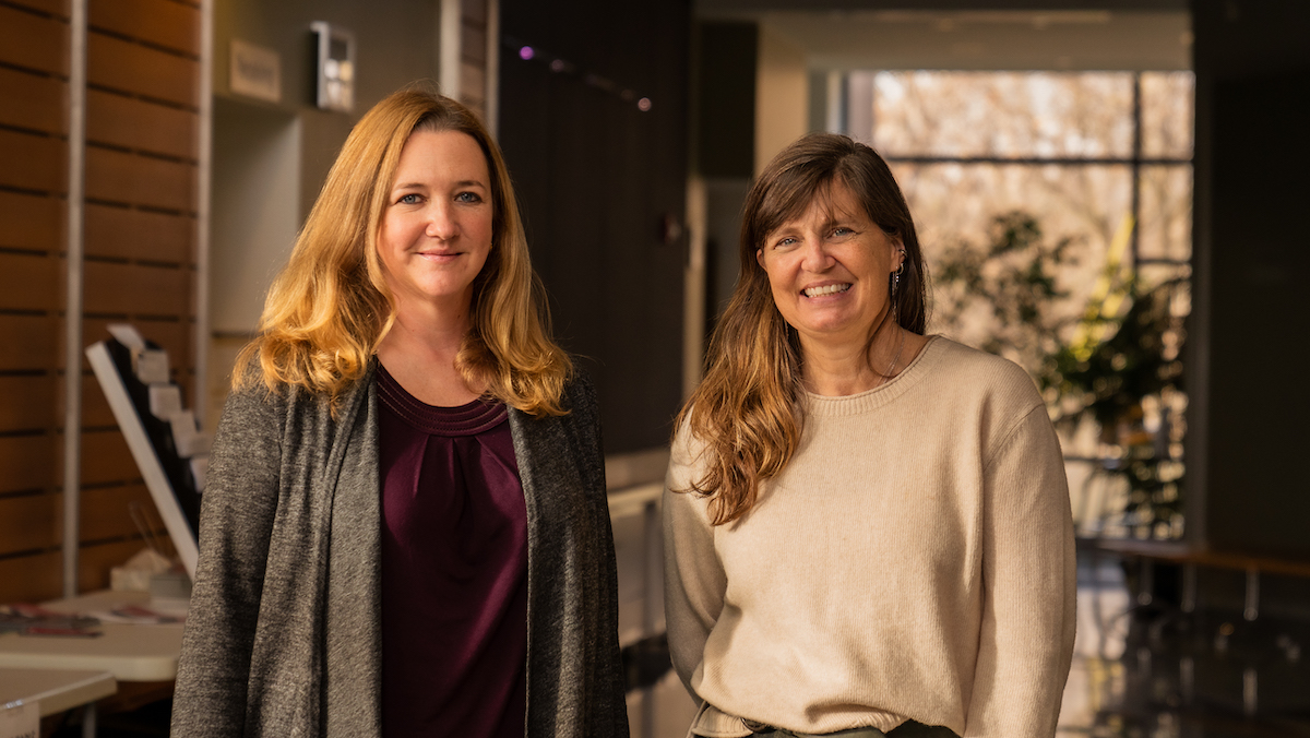 Dr. Krysten Schuler and Dr. Beth Bunting stand in the AHDC atrium in late afternoon