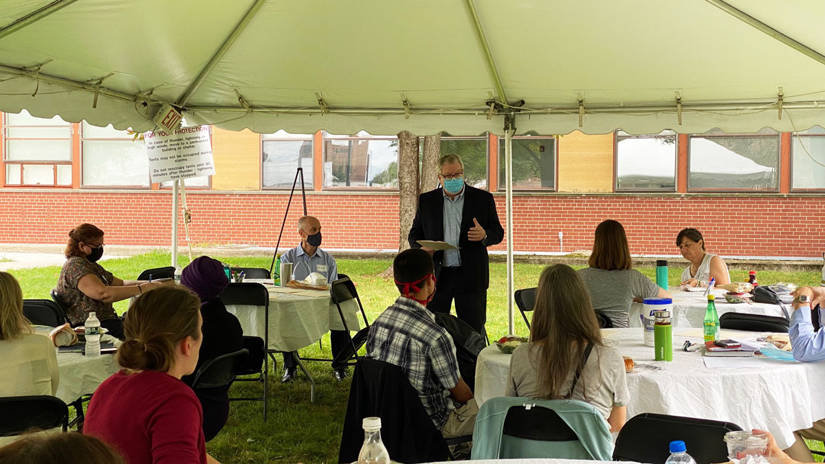 Dean Warnick speaks to a group of faculty in the new department beneath a tent outside the college