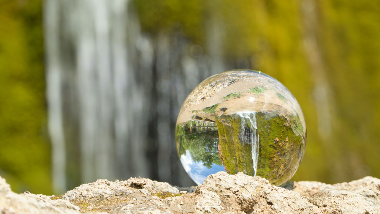 A stock photo of a waterfall reflected in a water droplet