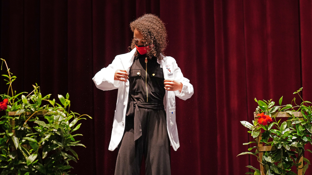 A student dons her white coat