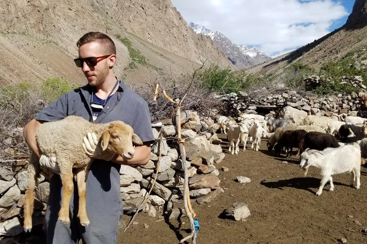 student with lamb in the mountains