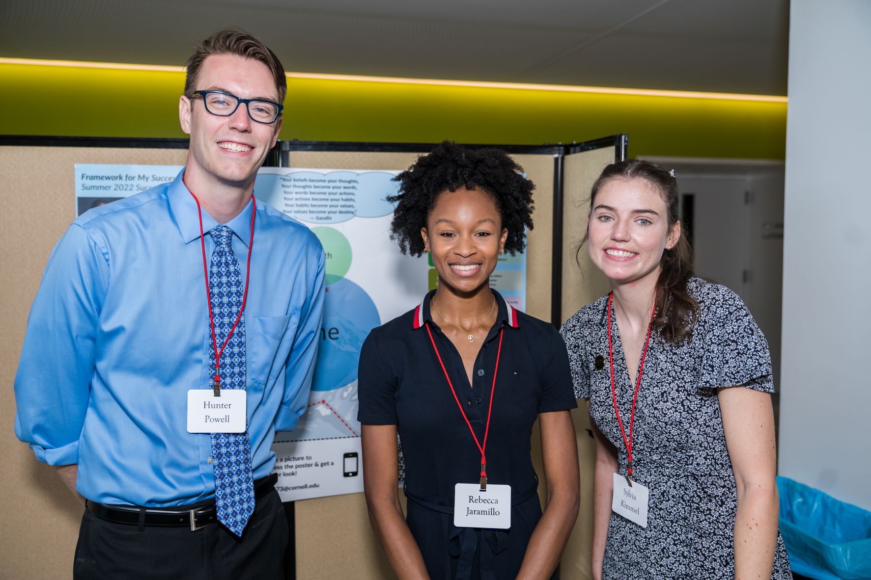 Three students in front of a poster