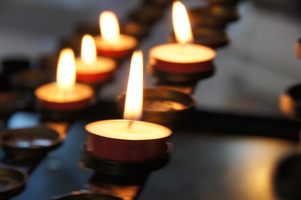 A group of tea candles lit in a dark church