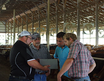 4 men in a barn around a computer