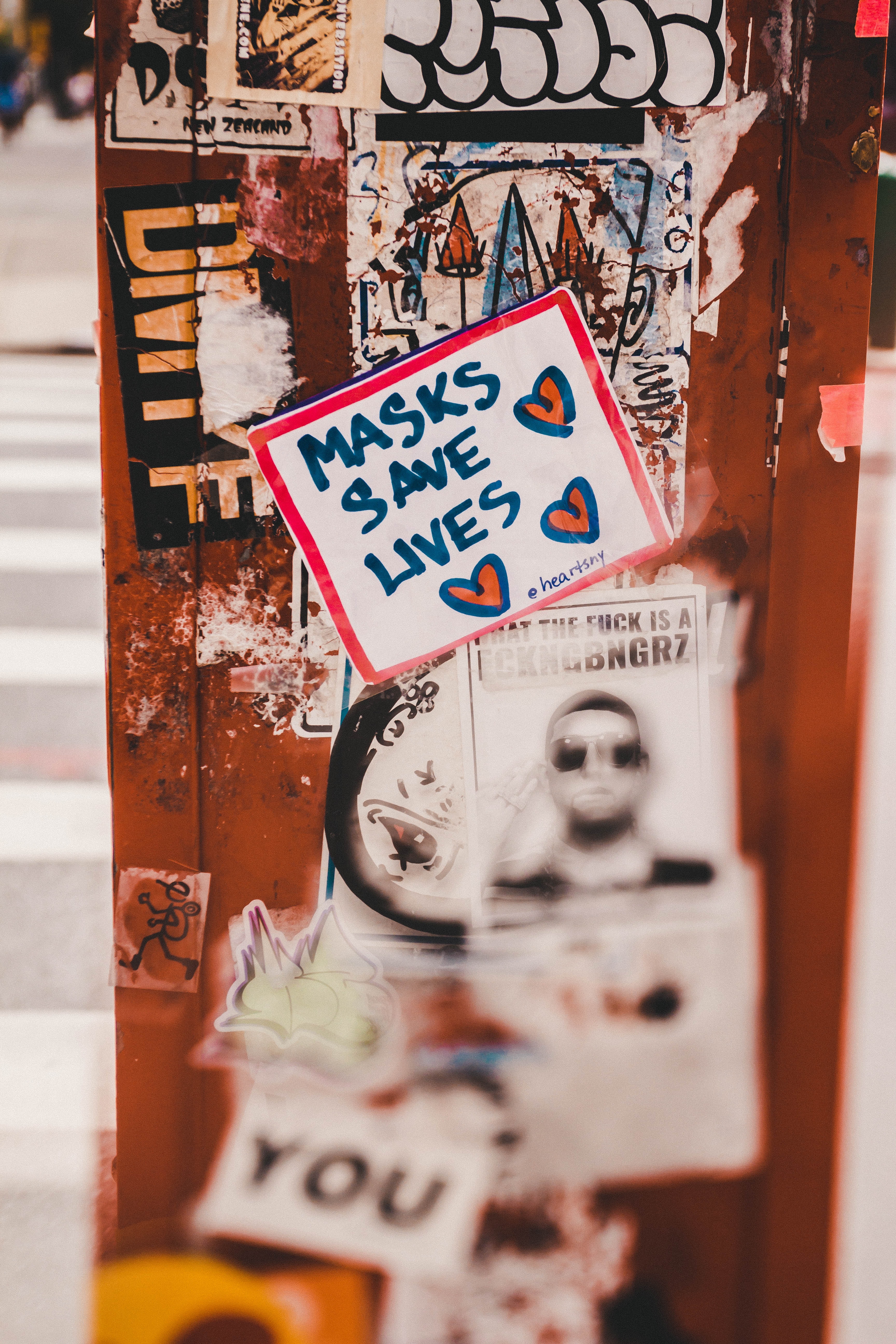 Close-up of several stickers on a door, the main focus on one reading 'masks save lives'