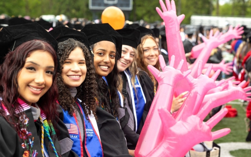 Class of 2025 at commencement holding the signature pink gloves