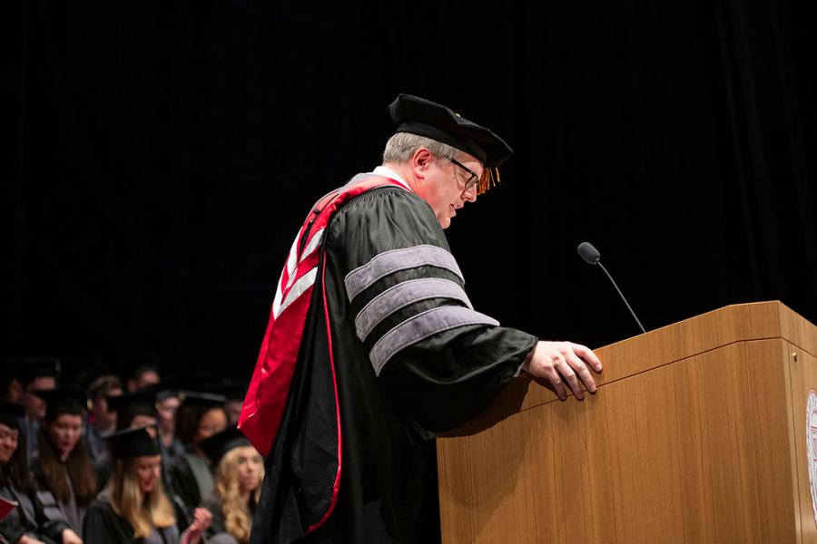 Dean Warnick at podium during hooding ceremony