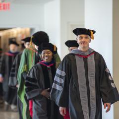 A line of faculty walking into the MPH 2019 hooding ceremony