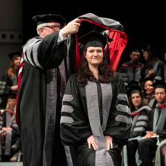 A student receives her hood from Dean Warnick