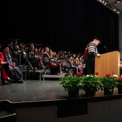 Dean Warnick at podium during hooding ceremony