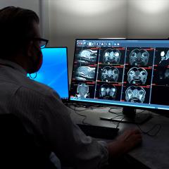 Imaging specialist reviewing MRI images on a computer