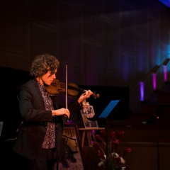 Fain playing violin in a dark room