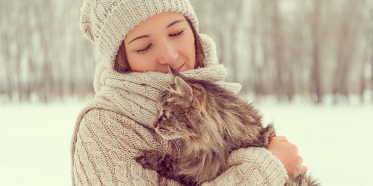 An woman hugging her cat outside in the snow