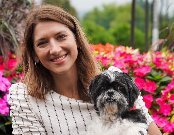 Coco holding dog Oliver in front of flowers