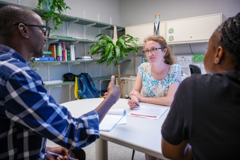 Three people sitting in an office talking.