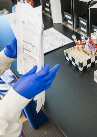 A gloved scientist sorting papers on a lab bench