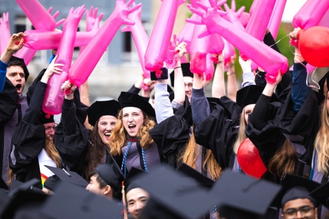 Class of 2025 at commencement holding the signature pink gloves
