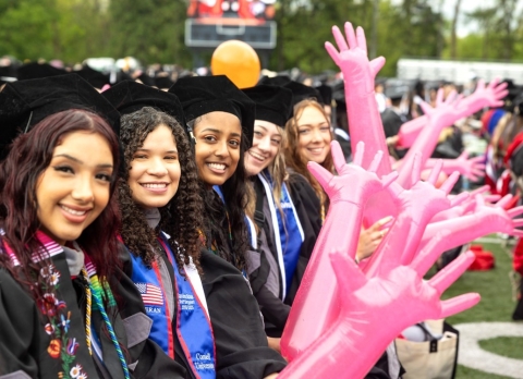 Class of 2025 at commencement holding the signature pink gloves