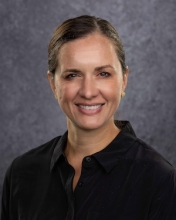 Aimee Colbath smiling at the camera while wearing a black button-up blouse.