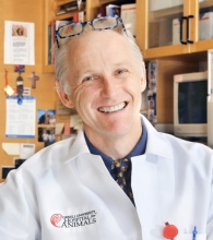 Headshot of Kenny Simpson in is lab wearing a white lab coat. 